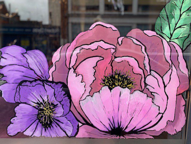 Hand‑painted window mural artwork of a colourful seasonal butterfly and flowers in a hair salon in Godalming, Surrey.