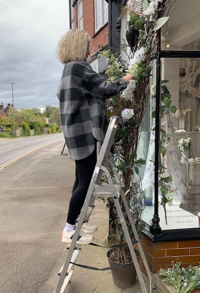 External faux‑flower arch installation at May & Grace, Haslemere Surrey, with Sarah Jamieson hand‑styling the display.