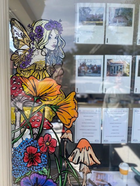 Hand‑painted shop window mural featuring bold, colourful illustrations designed to attract footfall for an independent business.