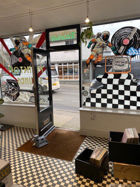 Hand‑painted window mural artwork of astronaut, vinyl turntable and lunar scene for Planet of Sounds record shop in Haslemere, Surrey.
